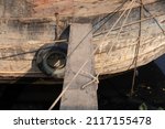 Small photo of Old wooden river boat with gangplank and ropes tied up at river on sunny day