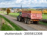 Small photo of Normandie, France, November 2008. Corn silage on muddy ground. Tractor and tipper on the road. Muck deposit and soiling of the road. Rural village in the background