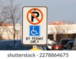A handicap parking restriction sign with a blue wheelchair symbol in a retail shopping plaza.