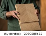 Checking pieces of wood, MDF with wooden veneer material in a woodworking workshop with a designer craftsman checking the quality and looking for improvements on his carpentry project 