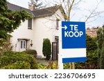 Small photo of House exterior facade with a sign saying ' Te Koop', for sale. Housing market, selling or buying property, investing in real estate concept. Dutch home surrounded by trees and greenery during winter