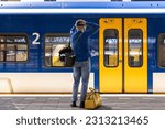 Small photo of Den Bosch, The Netherlands, May 30 2023. Man missing his train on the platform of the central train station while feeling sad and stressed on his Dutch travel journey arriving too late