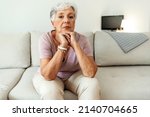 Small photo of Pensive thoughtful senior lady looking away, sit alone at home feel anxious lonely. Sad depressed melancholic old mature woman suffer from sorrow grief thinking of problem suffer from solitude.