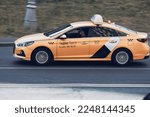 Small photo of Moscow, Russia - August 2022: orange Yandex taxi carin motion on Moscow street