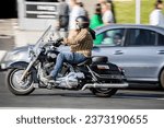 Small photo of Moscow, Russia - 29 September 2023: Side view rolling shot with motorcycle Harley Davidson moving on city street. Motorcyclist riding fast Harley-Davidson motorbike at urban street