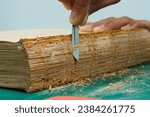 Small photo of Cleaning the spine of an ancient book before repair, glue deterioration, antique damage, repairing antique, repairing damaged books, steps for preserving antique books, close-up, depth of field