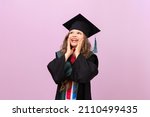 Small photo of A joyful beautiful graduate looks up. a schoolgirl in a graduate's robe and a master's hat. the child is happy to receive an education in another country.