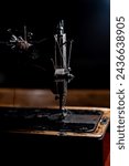 Small photo of An old sewing machine stands on the table at home ready to work and sew. Classic retro style manual sewing machine ready for sewing work. The machine is old style made of metal with floral patterns