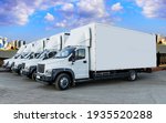 Small photo of Some trucks are parked in a parking lot next to a logistics warehouse by the river. Several trucks are lined up in the parking lot. Logistic transport