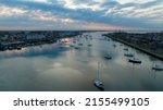 An aerial view over Sheepshead Bay, Brooklyn during a golden sunrise with boats anchored in the water. The drone camera is facing east towards the sun in a beautiful and cloudy sky.