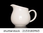 One ceramic milk jug, close-up, isolated on a black background.