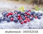 Pile of frozen lingonberries and blueberries, on frosty background