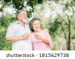 Happy Asian senior older couple drink coffee together outdoor in park