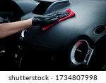 Small photo of Technician with gloves cleaning the car dashboard with red cloth. Topical car wash and care. protection of the interior of the automobile. cleaning, health and care concept.