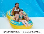 Two little girls on tube on water slide at aquapark. Summertime, vacation, entertainment, childhood concept. Colorful background.