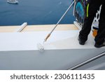 painting a white railing with a roller in Santorini