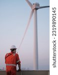 Small photo of Offshore technician. Seafarer. Seaman. Navigator. A man in a boiler suit is standing in front of the wind generator. Seafarer in front of the wing generator. Wind generator technician.