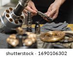 Small photo of Professional mechanic man holding Valve rod of the hydraulic piston pump to inspection and repair maintenance heavy machinery