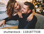 Happy charming woman dressed in knitwear talking to her handsome boyfriend spending time at cozy home, romantic couple in love happy about being together celebrating winter holidays in good mood