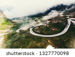 Bird's eye view of serpentine curves. Aerial view of scenic route in Austria with name Grossglockner High Alpine Road. Some of hairpin turns of Hochtor Pass. cloudy sky and snowy mountains