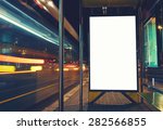 Illuminated blank billboard with copy space for your text message or content, advertising mock up banner of bus station, public information board with blurred vehicles in high speed in night city