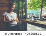 Charming woman with beautiful smile reading good news on mobile phone during rest in coffee shop, happy Caucasian female watching her photo on cell telephone while relaxing in cafe during free time 