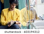 Handsome thoughtful male writer noting best ideas for magazine article about restaurant review planning strategy in personal diary organizing ideas to create successful material for front page