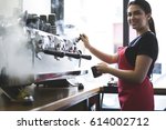 Small photo of Smiling busty female barista using professional coffee machine enjoying job in cafe improving skills of making cappuccino, charming young trainee in uniform learning how to temperate drinks with steam