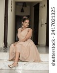Small photo of ISLAMABAD, PAKISTAN - JANUARY 13, 2024 :Young beautiful classy girl sitting on the floor in short frock dress in comfortable home interior