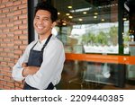 Small photo of young hispanic business owner smile and hold tablet for check order from customer stand on wall of blurred restaurant cafe shop background for SME new small business and franchise investment concept