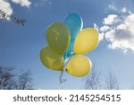 Small photo of light yellow and blue helium balloons fly in sky. color of flag of Ukraine. Illusory hopes for happiness during military operations on territory of Ukraine. symbol of freedom and joy for Ukrainians