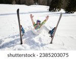 young woman or teenage girl in good mood while skiing fell and lies cheerfully in the snow. enjoying the moment, digital detox, positive thinking. Interesting active winter holiday, healthy lifestyle