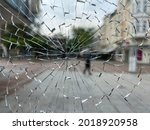 A street with a pedestrian seen through a broken window. Probably a case of vandalism.