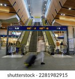 Small photo of London, UK - Mar 22 2023: People in London Bridge railway station with motion blur. Station concourse with escalators to platforms. London Bridge station is a transport hub in Greater London.