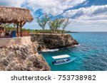 Negril, Jamaica, Caribbean rocky beach with turquoise water, tourists boat and lighthouse. 