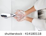 Woman in a bathrobe is washing hands.