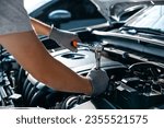 Small photo of Mechanic using wrench while working on car engine at garage workshop, Car auto services and maintenance check concept.