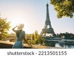 Small photo of Rear view of woman tourist in sun hat standing in front of Eiffel Tower in Paris at sunset. Travel in France, tourism concept. Holiday or vacation in Paris