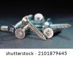 Macro photo of Screws in a pile - selective focus, shallow depth of field, dark background with cool blue light