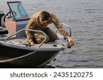 Small photo of Canada Ottawa - March 8, 2024 motor boat with fisherman on the rive