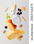 Small photo of Different types of cheese are flying or falling in the air. Levitation concept. Cheeses mix or set maasdam, dor blue, camembert, brie and grapes, walnuts, galeta. Isolated. Copy space.