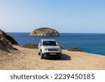 Small photo of Vacation with a rental car. 4x4 offroad Jeep Renegade in front of the bay with turquoise water. Discover the Mediterranean islands. Travel to summer vacation. Rhodes island, Greece. October 09.2022