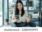 Small photo of Asian girl shopping online holding credit and using smartphone enter their card number in the mobile phone app to purchase and payment in internet store.
