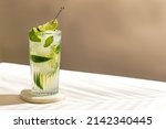 cold Mojito cocktail with rum, lime, ice cubes and mint. Tropical palm leaf shadow. Sunlight and shadow background. beige minimal