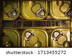 Photo of real authentic typeset letters forming capitalized Be Prepared text between canned food flatlay on vintage textured grunge copper and gold background