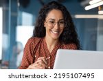 Small photo of Close-up photo of young beautiful business woman with curly hair and glasses Hispanic woman talking on video call using laptop for remote communication and conference