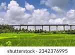 Small photo of Super fast train crosses long viaduct at scenic location of green fields on Konkan Railway route.