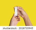 Hand holds a test swab cartridge isolated on yellow. COVID-19 Ag rapid self test kits. Antigen or Antibody test. Virus disease healthcare check. Coronavirus outbreak.