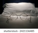 Small photo of An eyeglasses optics on white linen bed, low light night time, shortsighted, nearsighted, farsighted, eyewear business products, relax or rest or sleeping time concept, focus on foreground