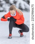 Small photo of A young fit woman holds a reinforced knee after straining her cruciate ligament during cross-country training in the snow during the winter season.
